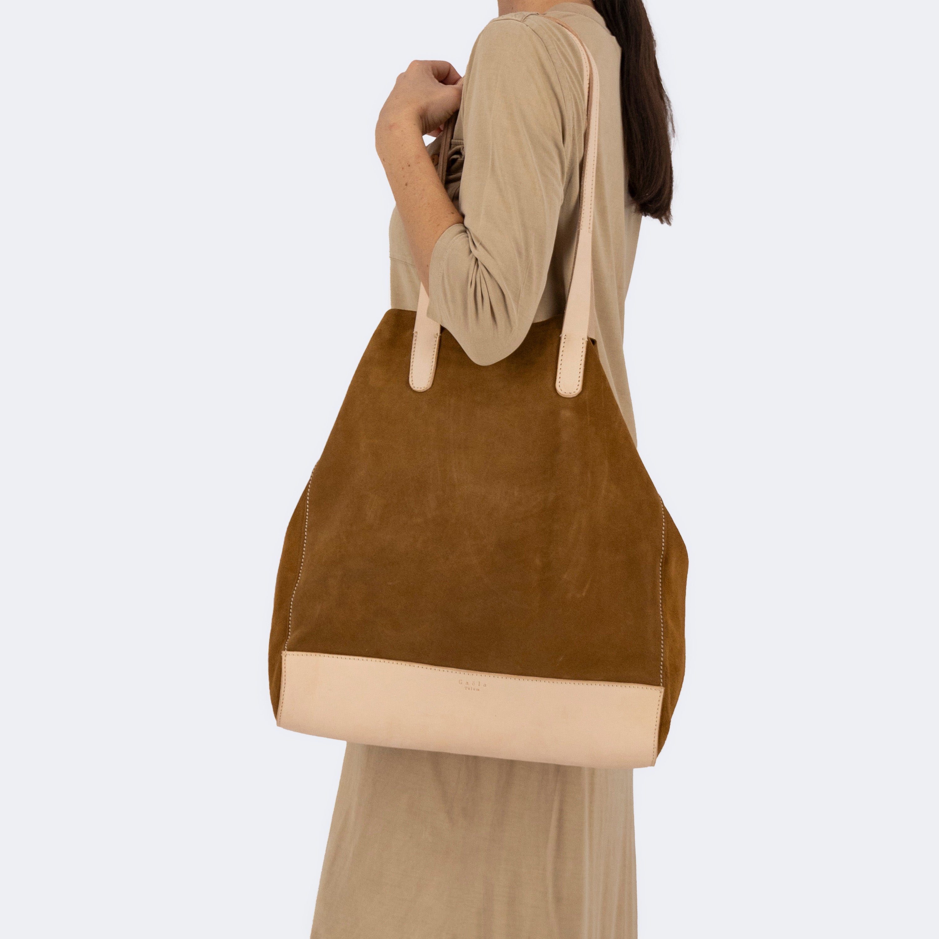 Model carrying The Tote Bag in brown suede with leather accents, showcasing its soft structure and minimalist design.