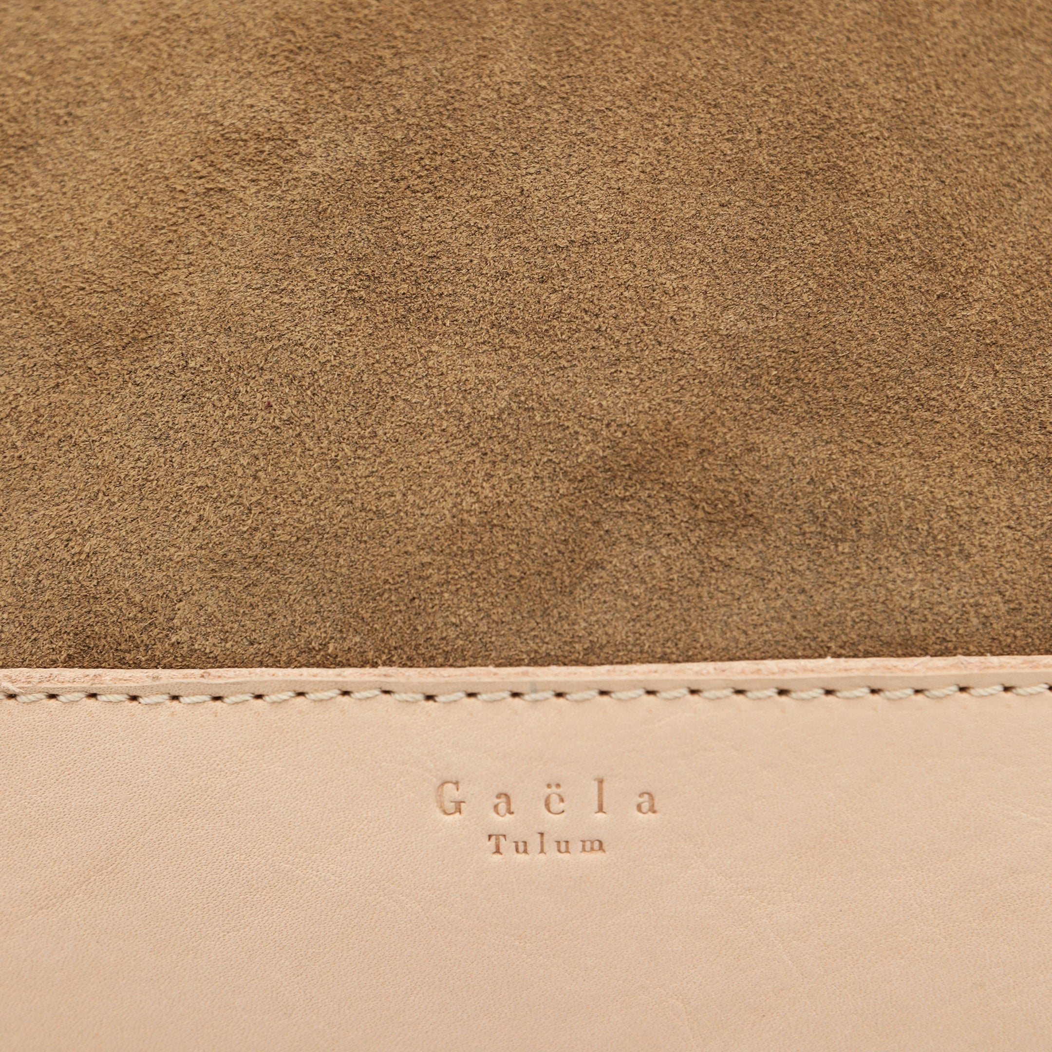 Close-up of The Tote Bag in sand suede, highlighting the texture of the fabric, leather detailing, and visible stitching.