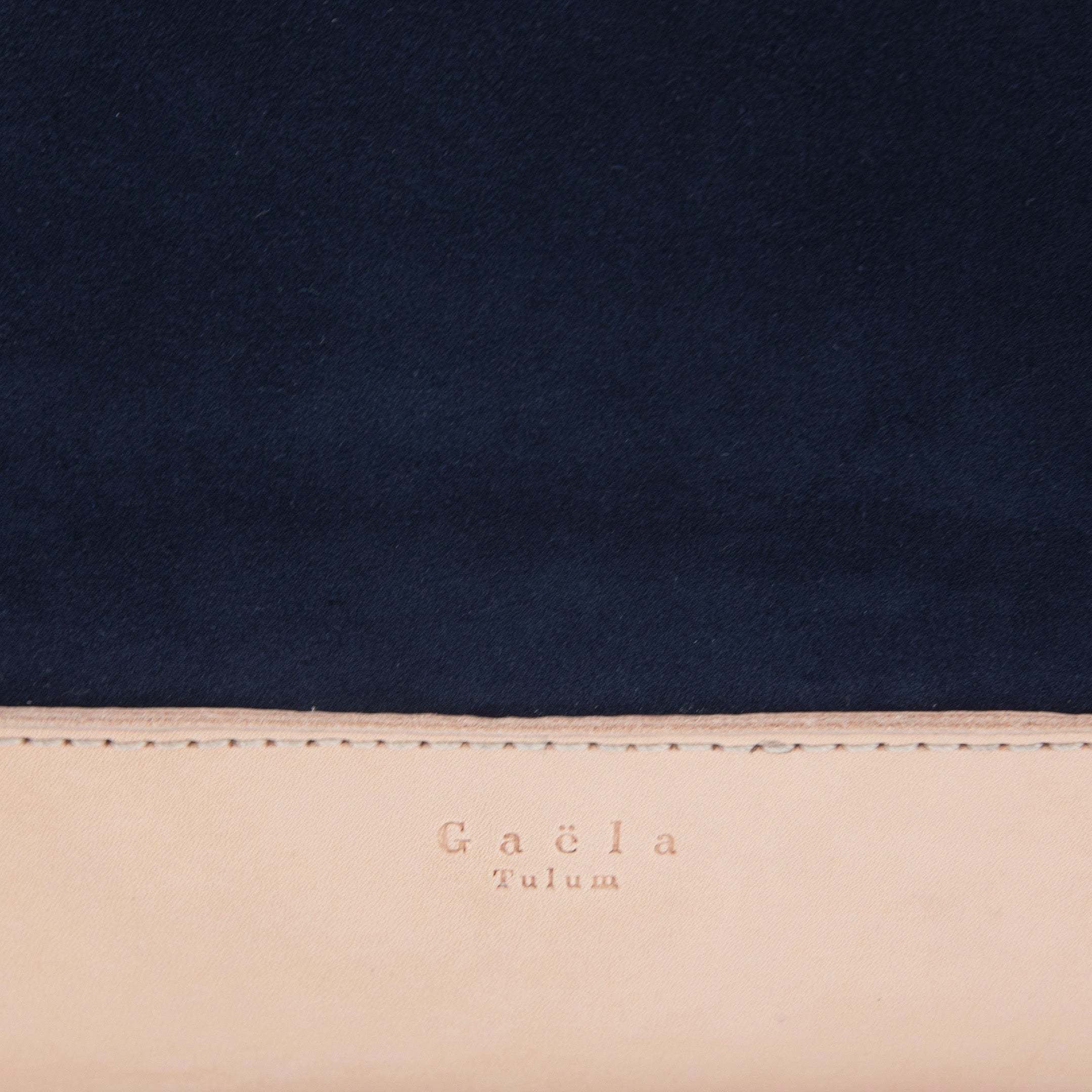 Close-up of The Tote Bag in navy blue suede, highlighting the texture of the fabric, leather detailing, and visible stitching.