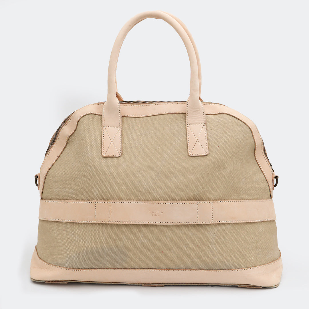 Back view of The Weekender in tan, showing the built-in luggage band that slides over a suitcase handle for easy travel.