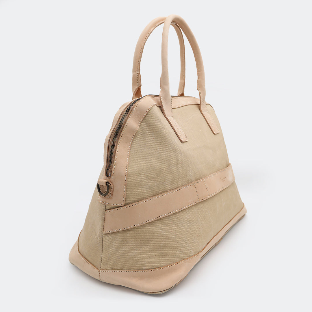 The Weekender in tan, crafted from waxed cotton with full-grain leather accents — a spacious travel bag with a clean silhouette and curved handles.