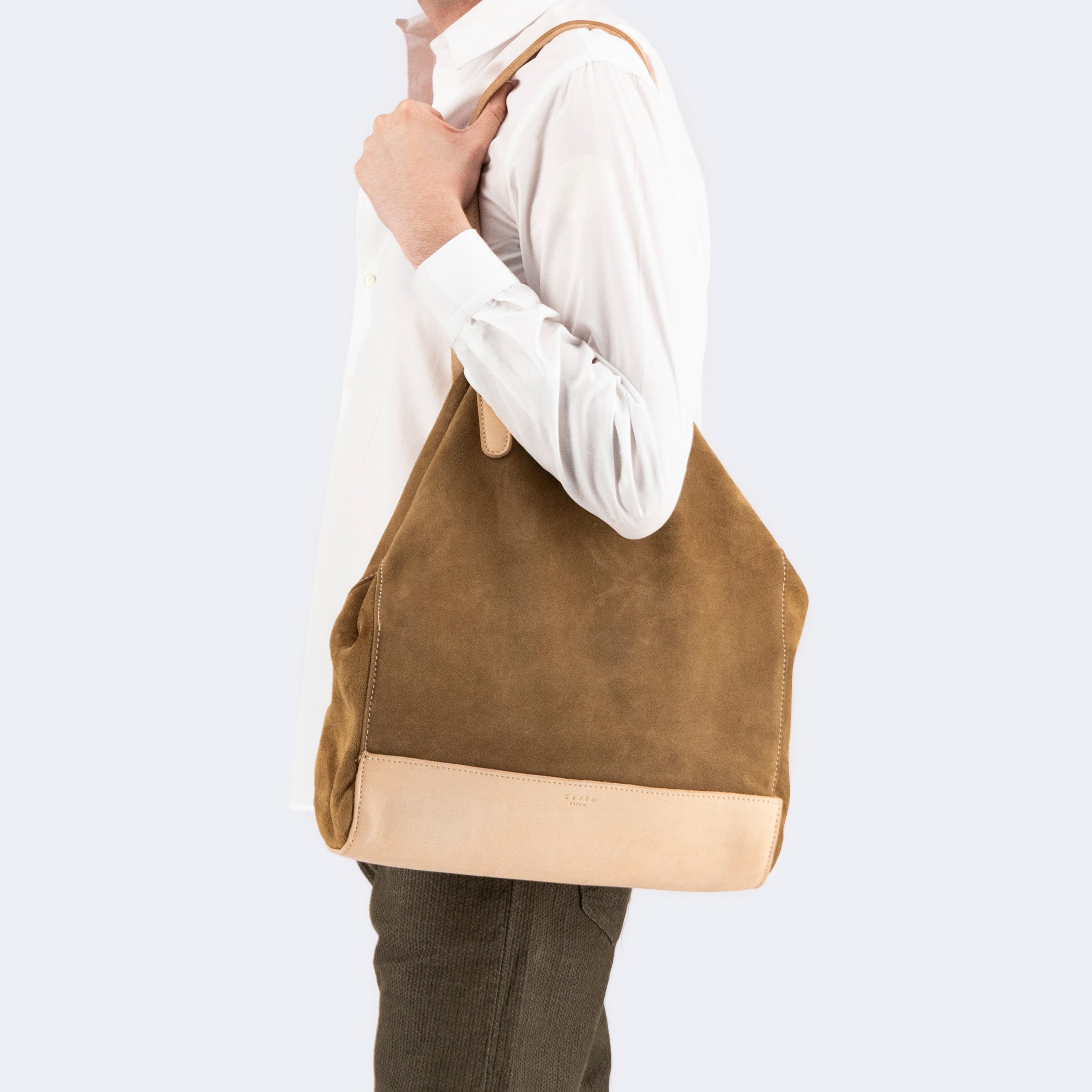Model carrying The Tote Bag in brown suede with leather accents, showcasing its soft structure and minimalist design.
