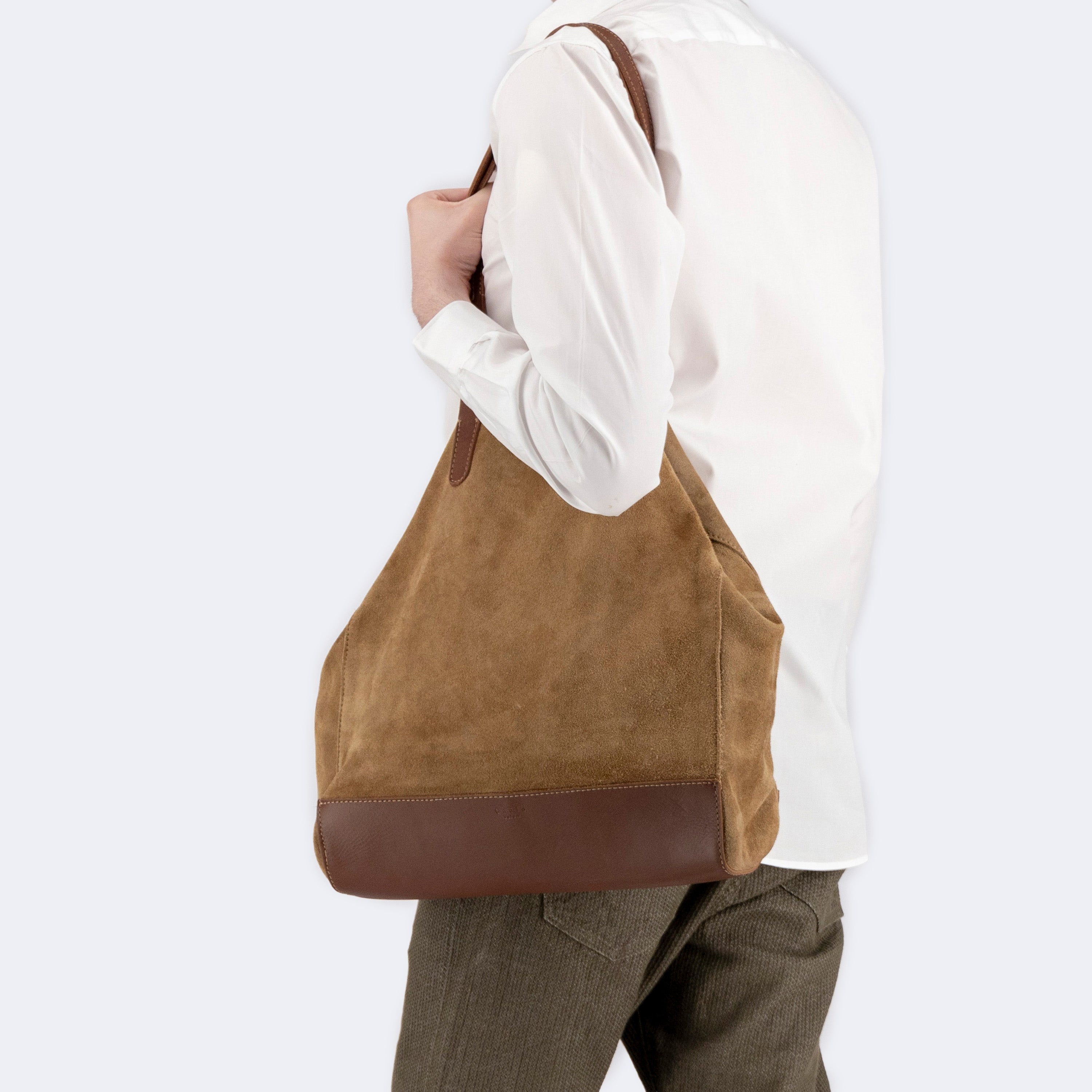 Model carrying The Tote Bag in brown suede with leather accents, showcasing its soft structure and minimalist design.