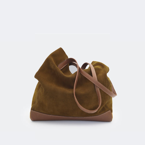 The Tote Bag in brown suede with full-grain leather accents on the base and handles, featuring a minimalist silhouette and structured shape.
