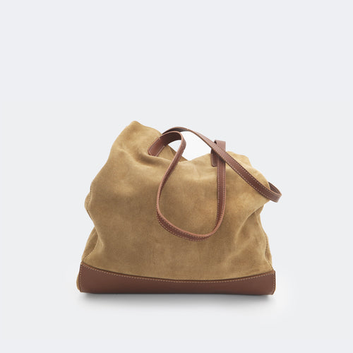 The Tote Bag in brown suede with full-grain leather accents on the base and handles, featuring a minimalist silhouette and structured shape.