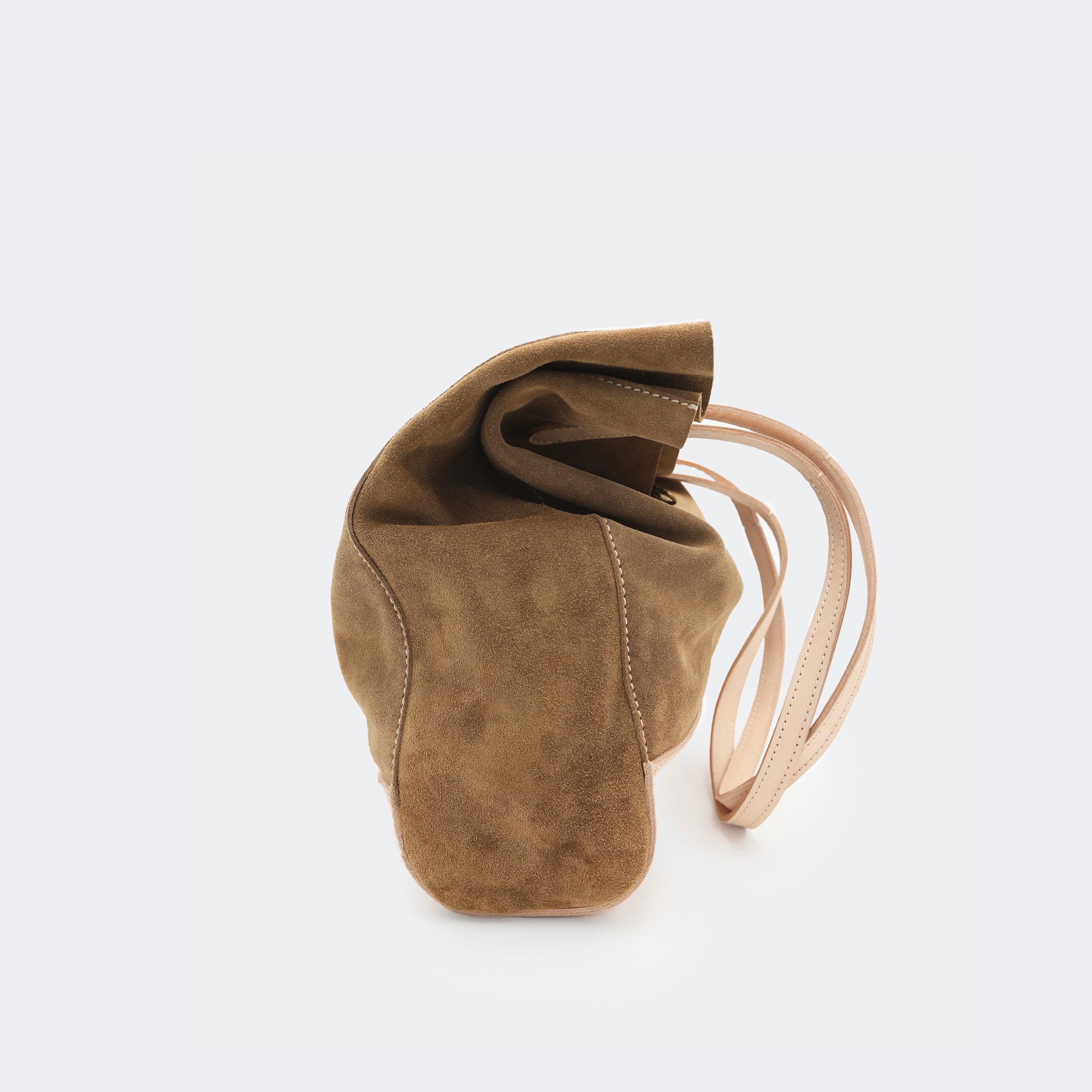 Side view of The Tote Bag in brown suede with leather accents, shown relaxed and partially slouched to highlight its soft, unstructured form.