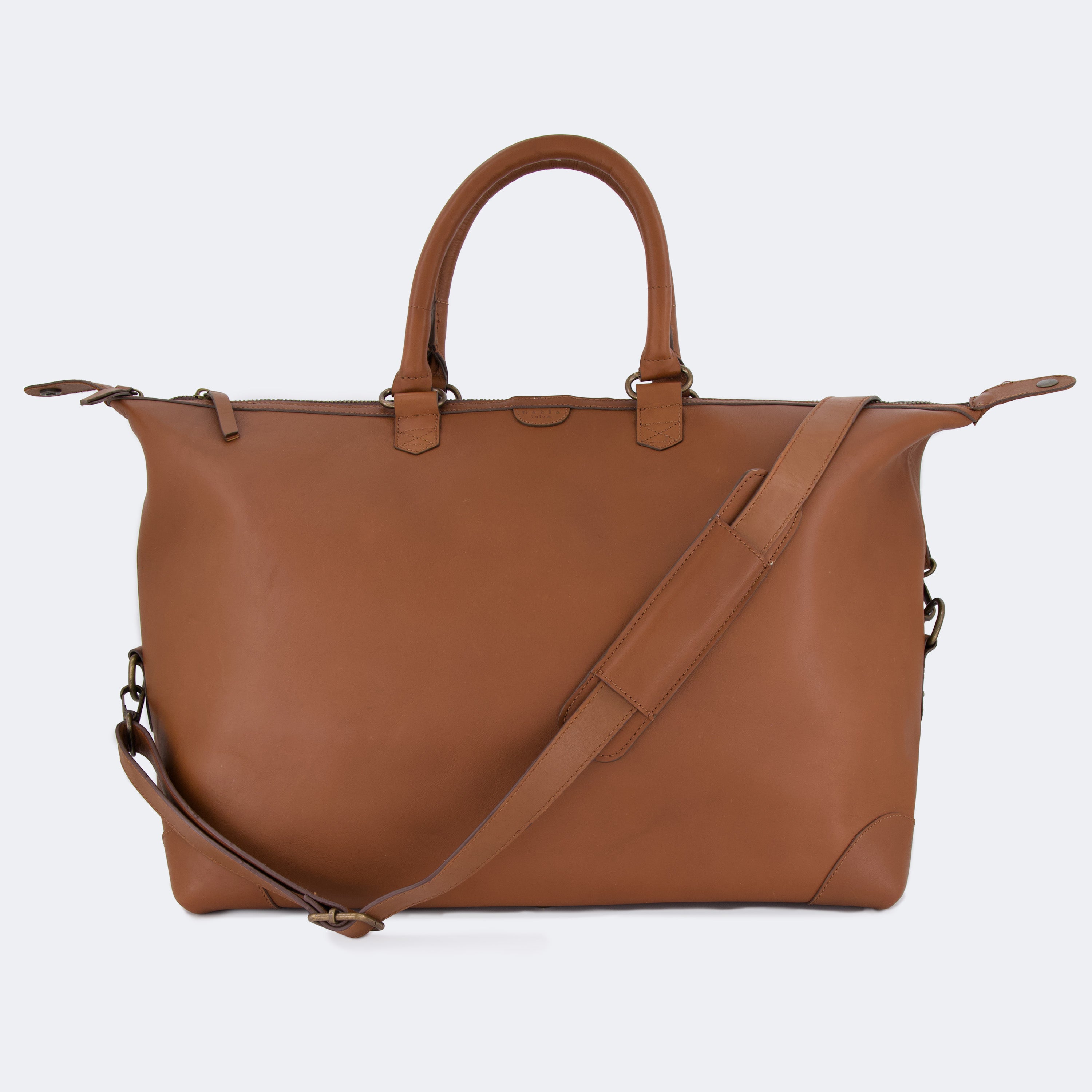 The Valise in brown leather, shown with its removable full-grain leather shoulder strap attached — designed for hands-free carry and versatile travel.