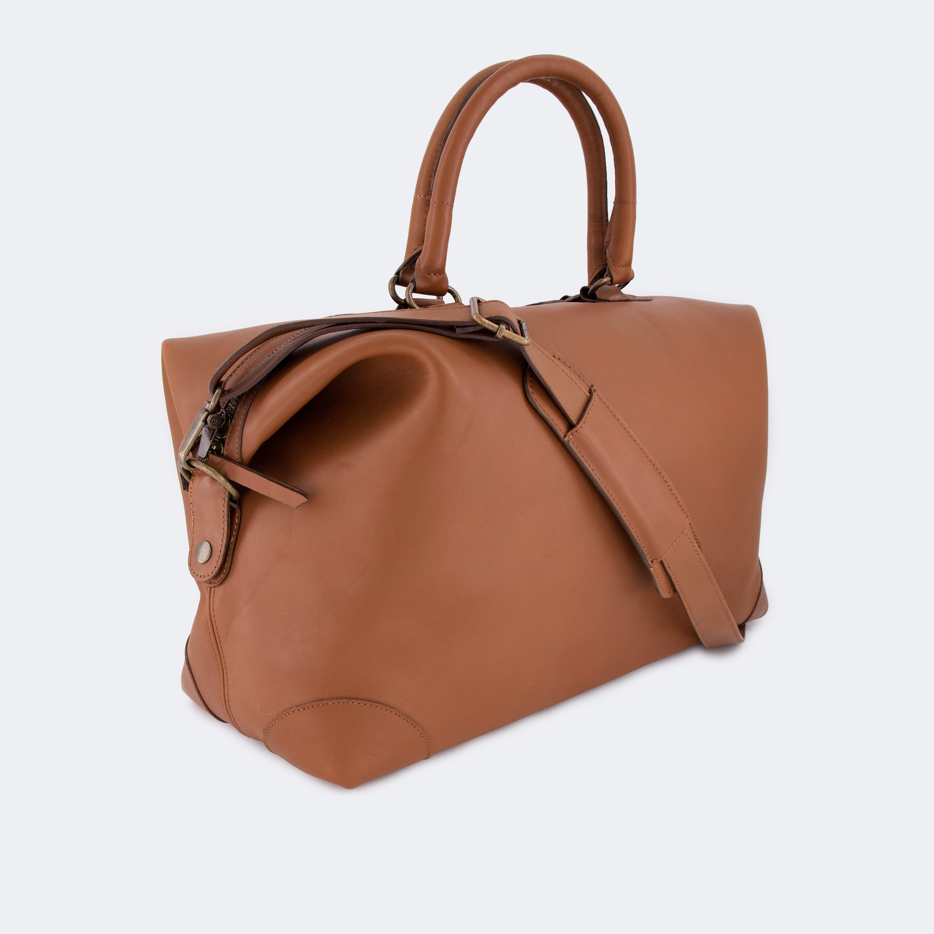 The Valise in brown leather, shown with its removable full-grain leather shoulder strap attached — designed for hands-free carry and versatile travel.