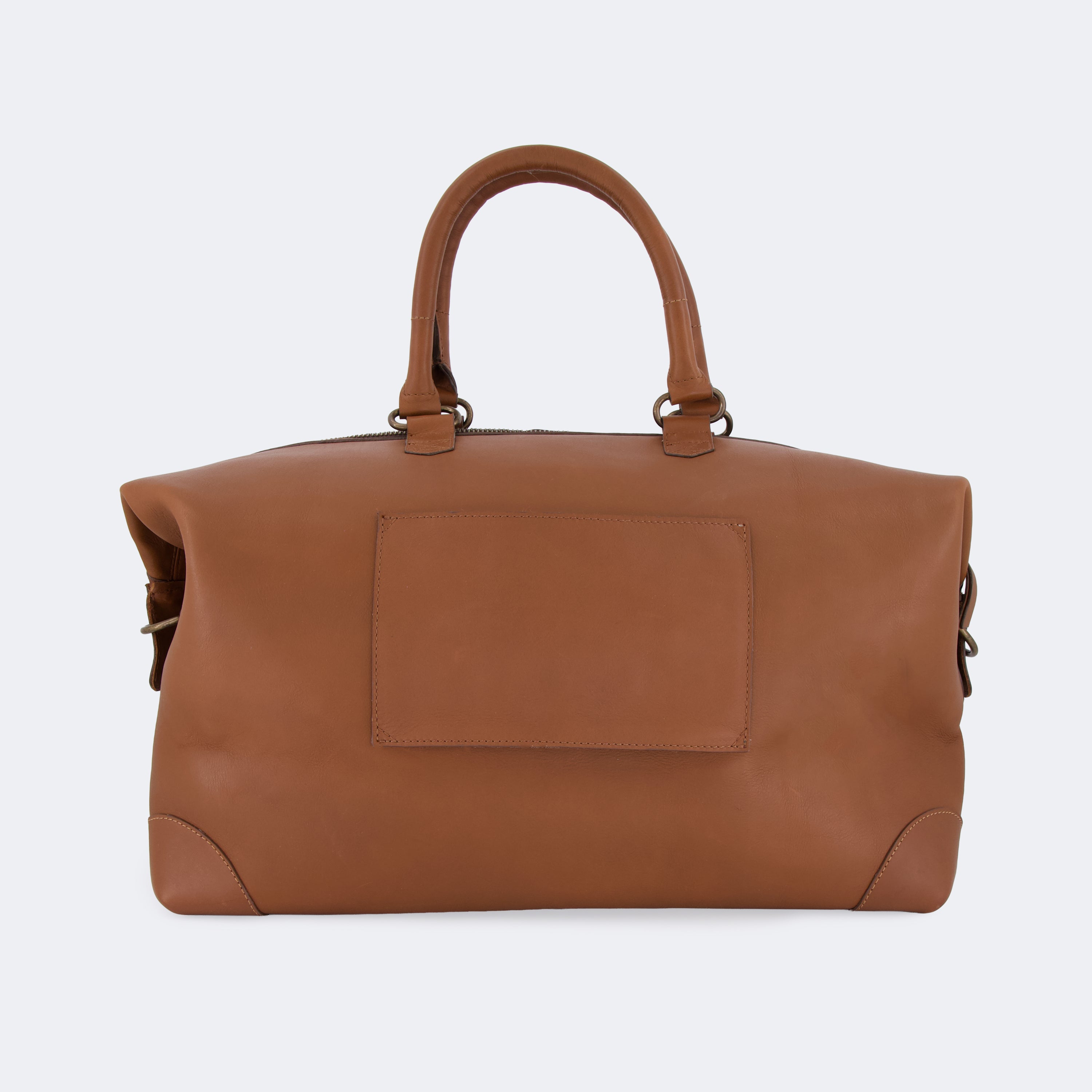 The Valise in brown leather shown from behind, highlighting the integrated luggage band designed to slide over a suitcase handle.