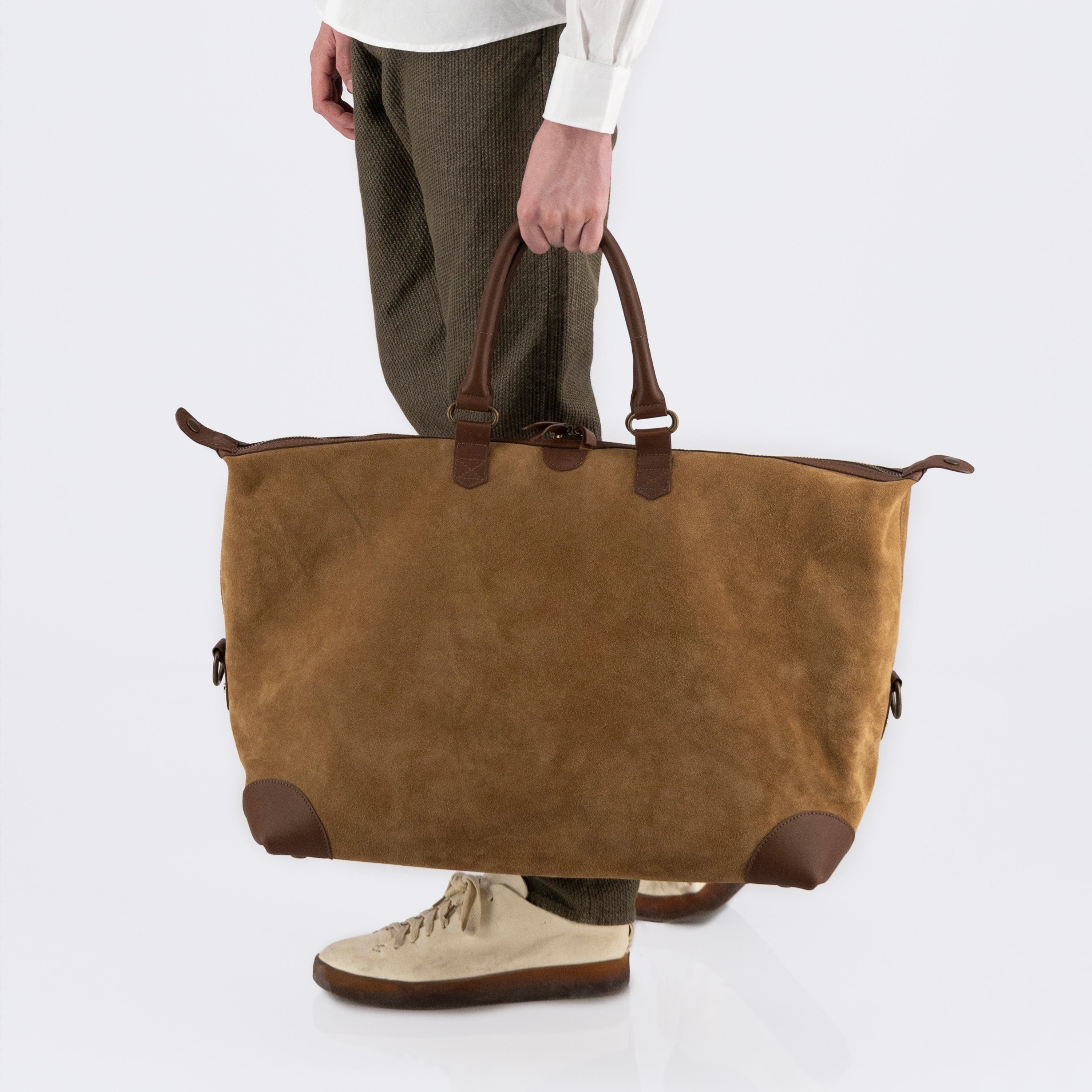 The Valise in brown leather, carried by a model and expanded to full capacity with snap closures open — showcasing its spacious design and versatile silhouette.