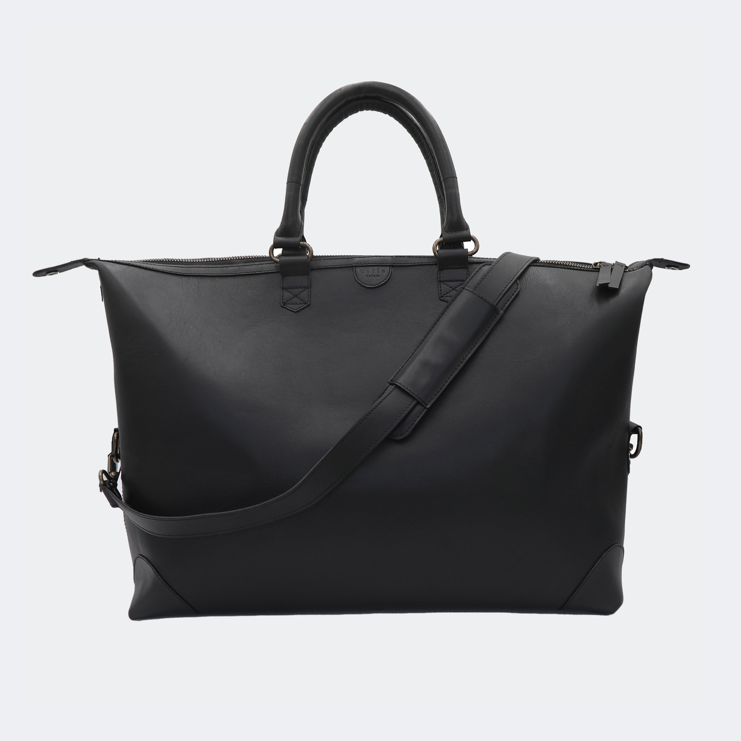 The Valise in black leather, shown with its removable full-grain leather shoulder strap attached — designed for hands-free carry and versatile travel.