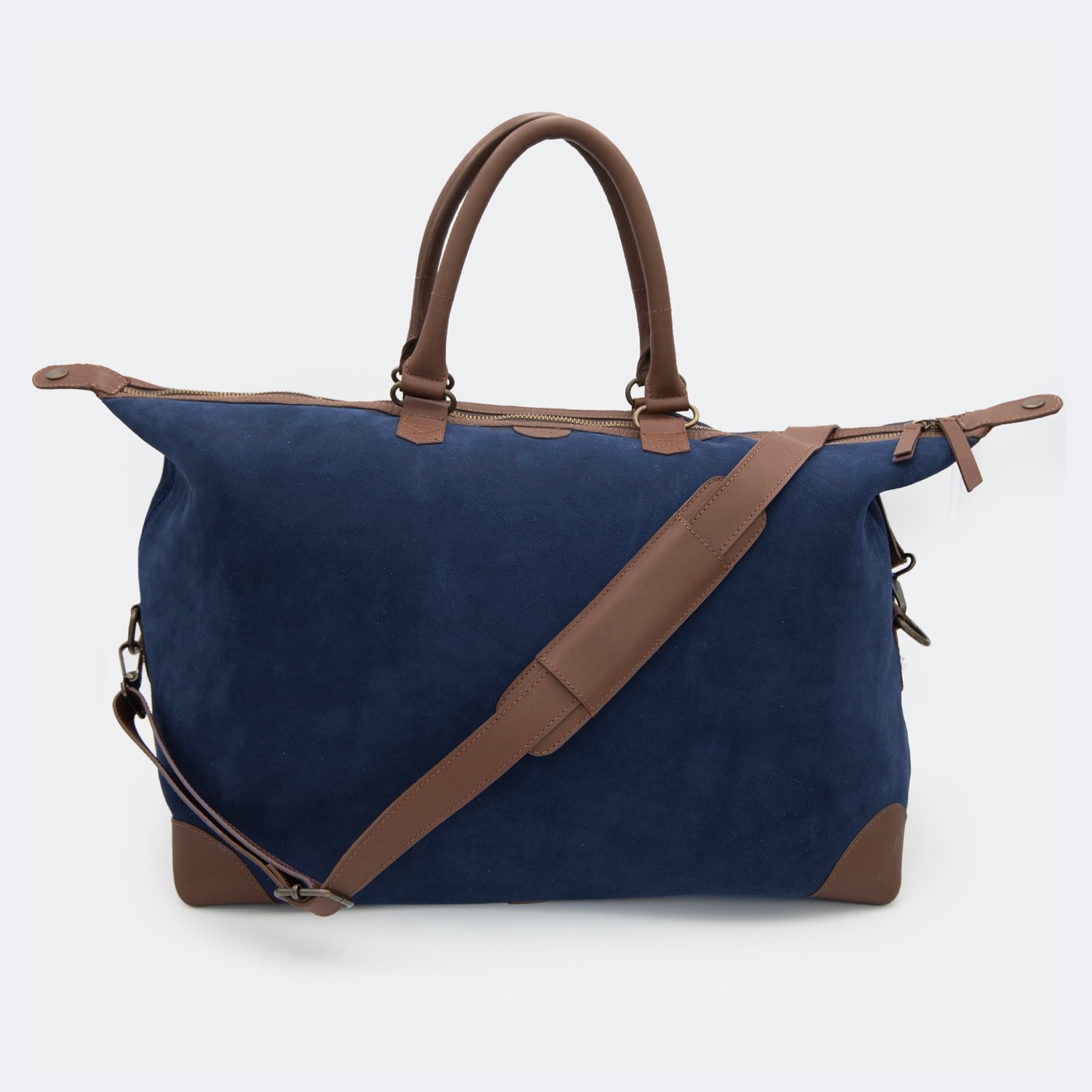 The Valise in navy blue leather, shown with its removable full-grain leather shoulder strap attached — designed for hands-free carry and versatile travel.
