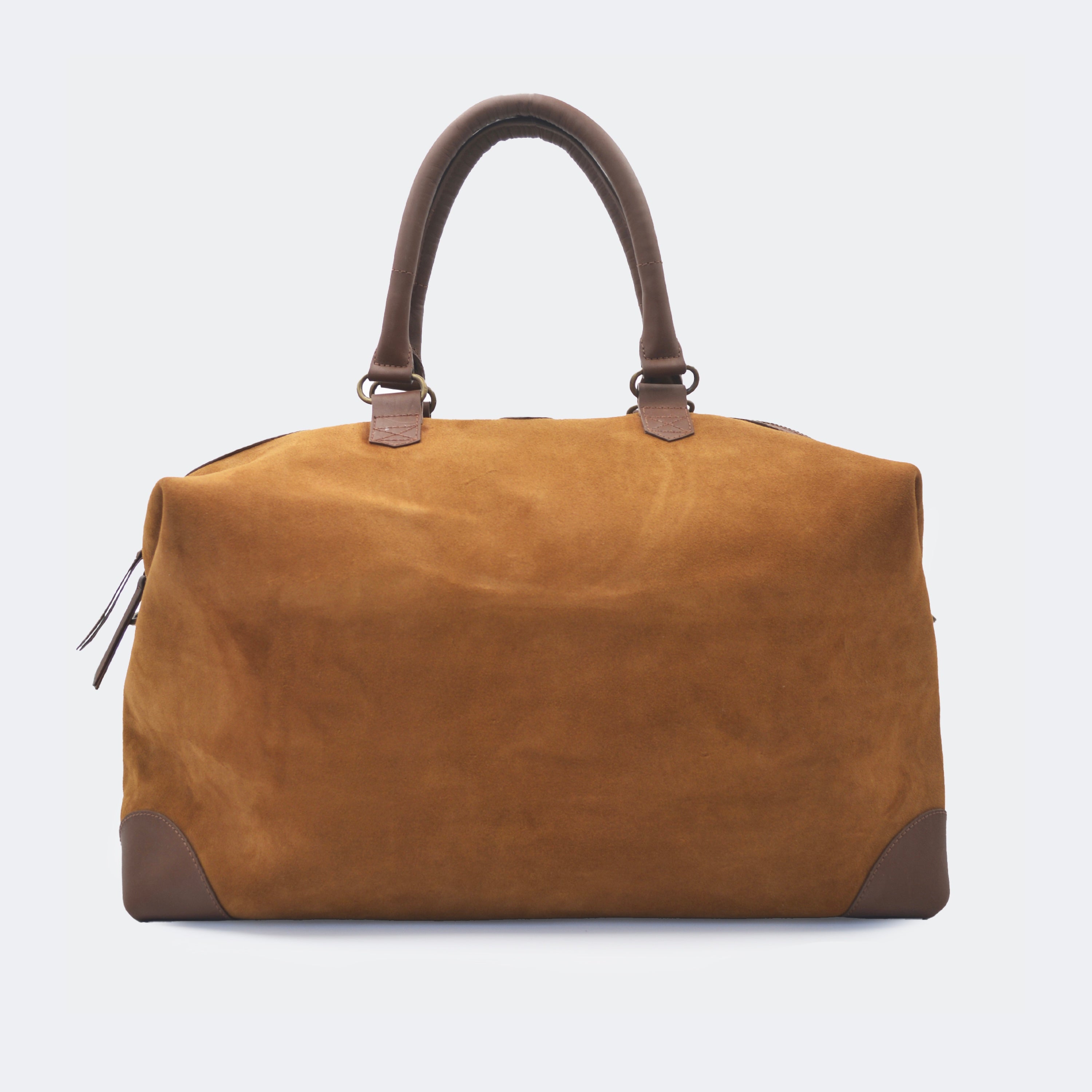 The Valise in brown leather, crafted from full-grain leather with structured sides and curved handles — a minimalist travel bag blending elegance and utility.