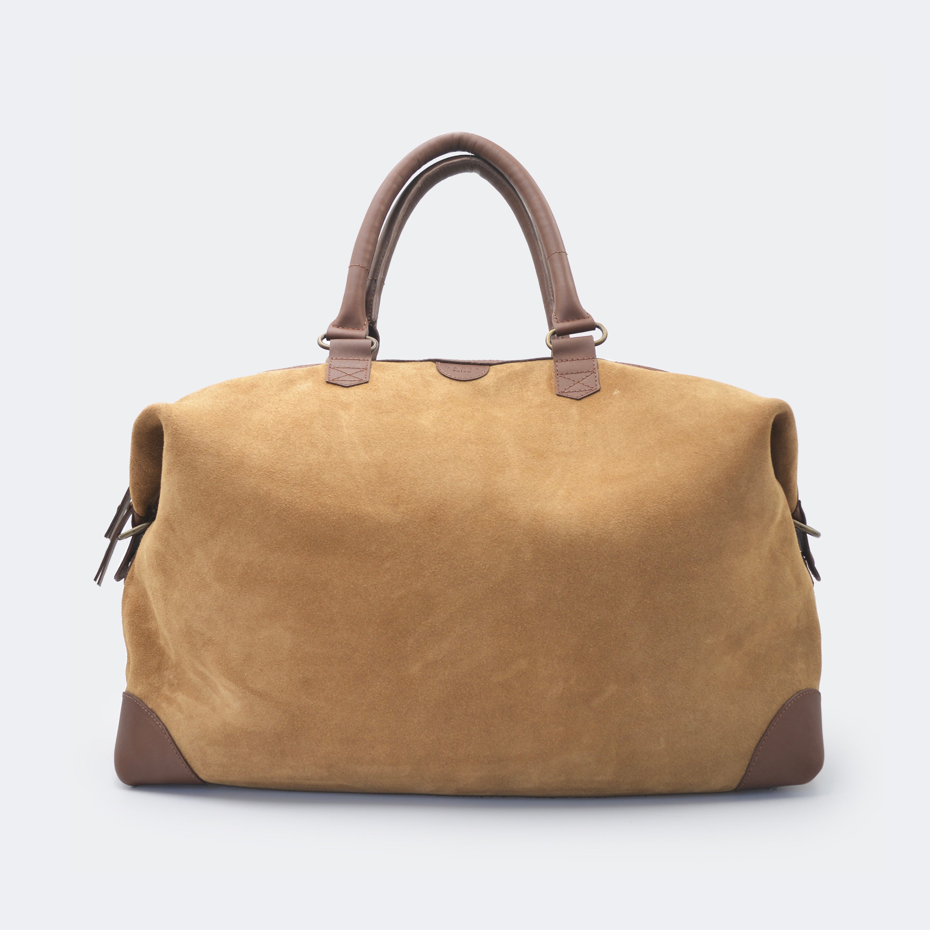 The Valise in brown leather, crafted from full-grain leather with structured sides and curved handles — a minimalist travel bag blending elegance and utility.
