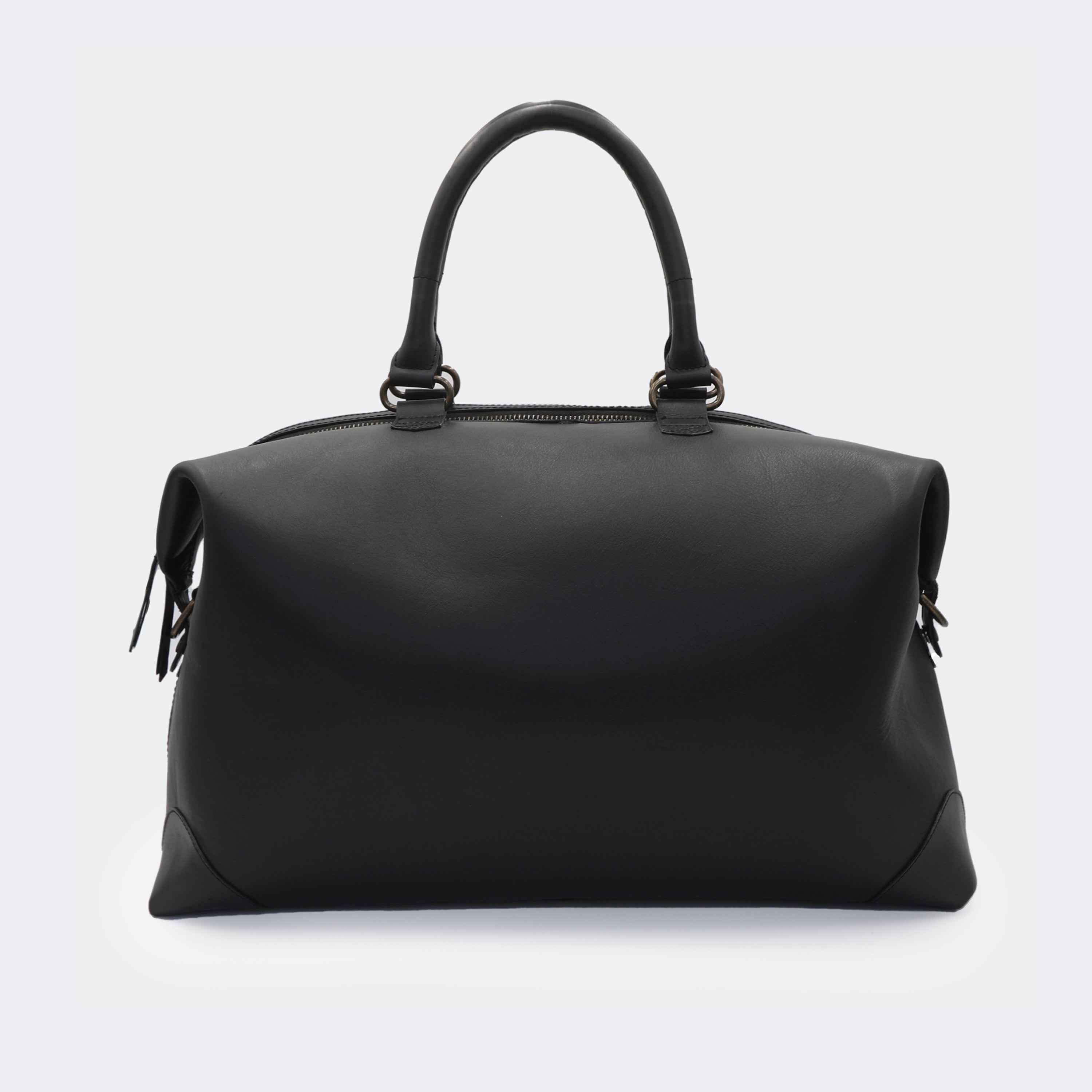 The Valise in black leather, crafted from full-grain leather with structured sides and curved handles — a minimalist travel bag blending elegance and utility.