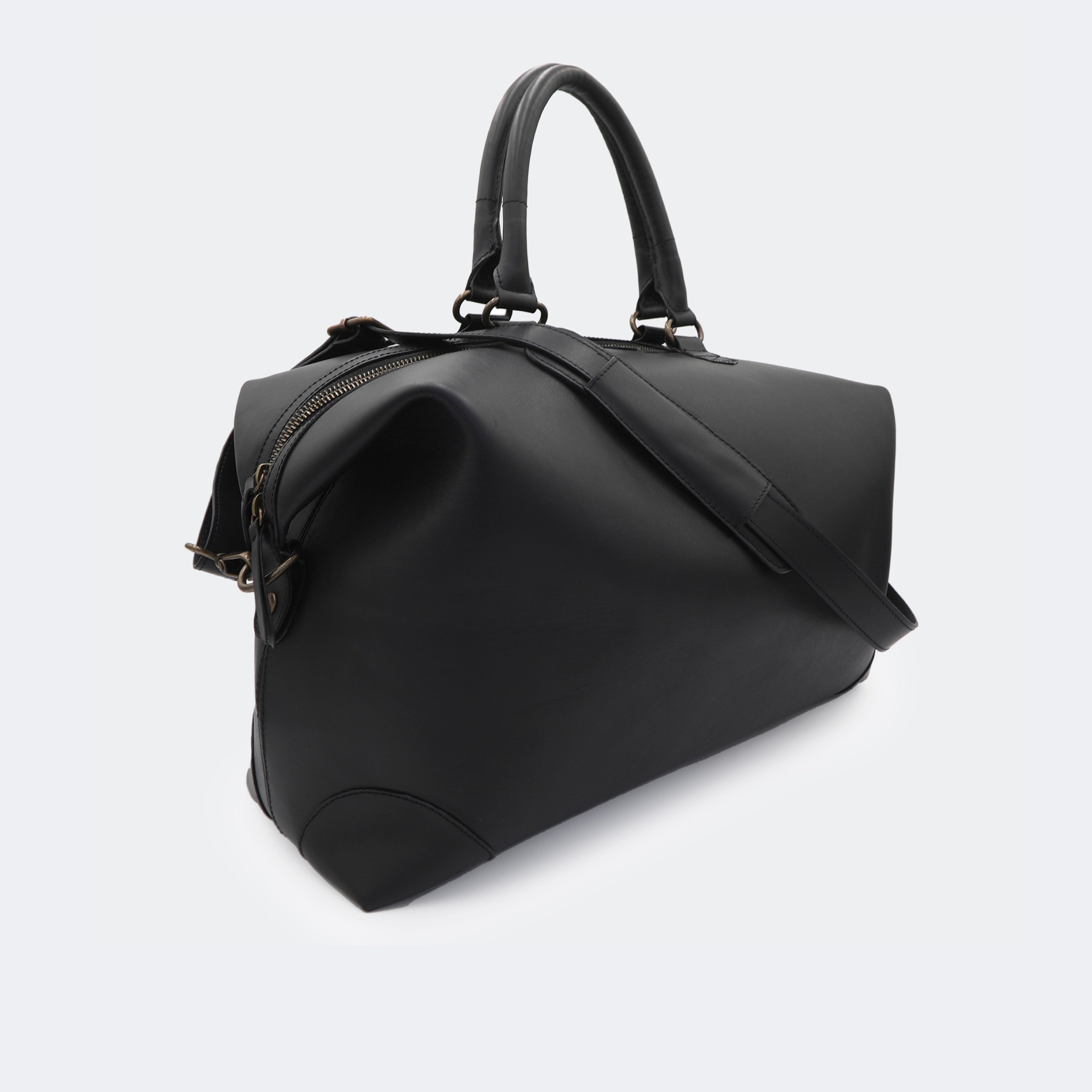 The Valise in black leather, shown with its removable full-grain leather shoulder strap attached — designed for hands-free carry and versatile travel.