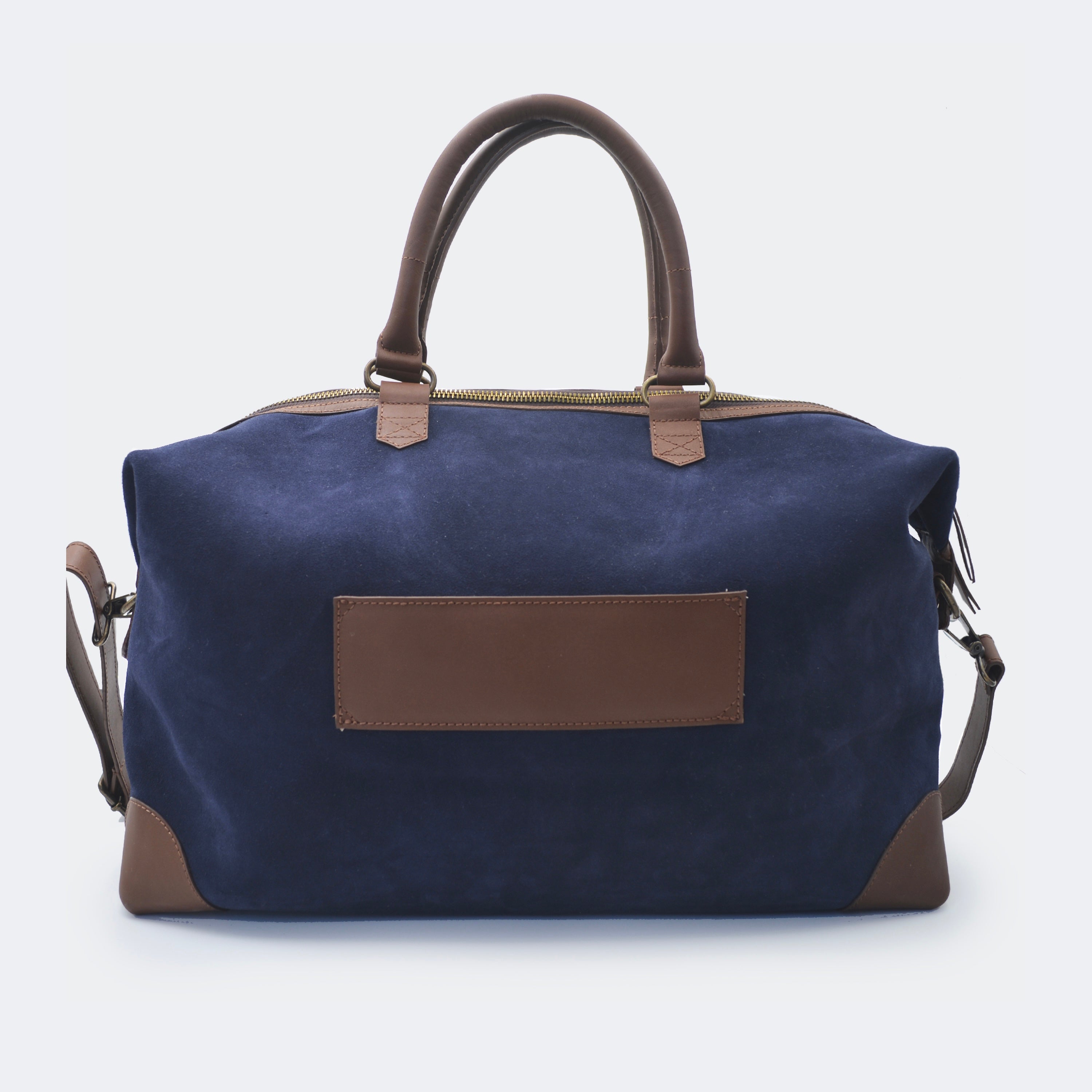 The Valise in navy blue leather shown from behind, highlighting the integrated luggage band designed to slide over a suitcase handle.