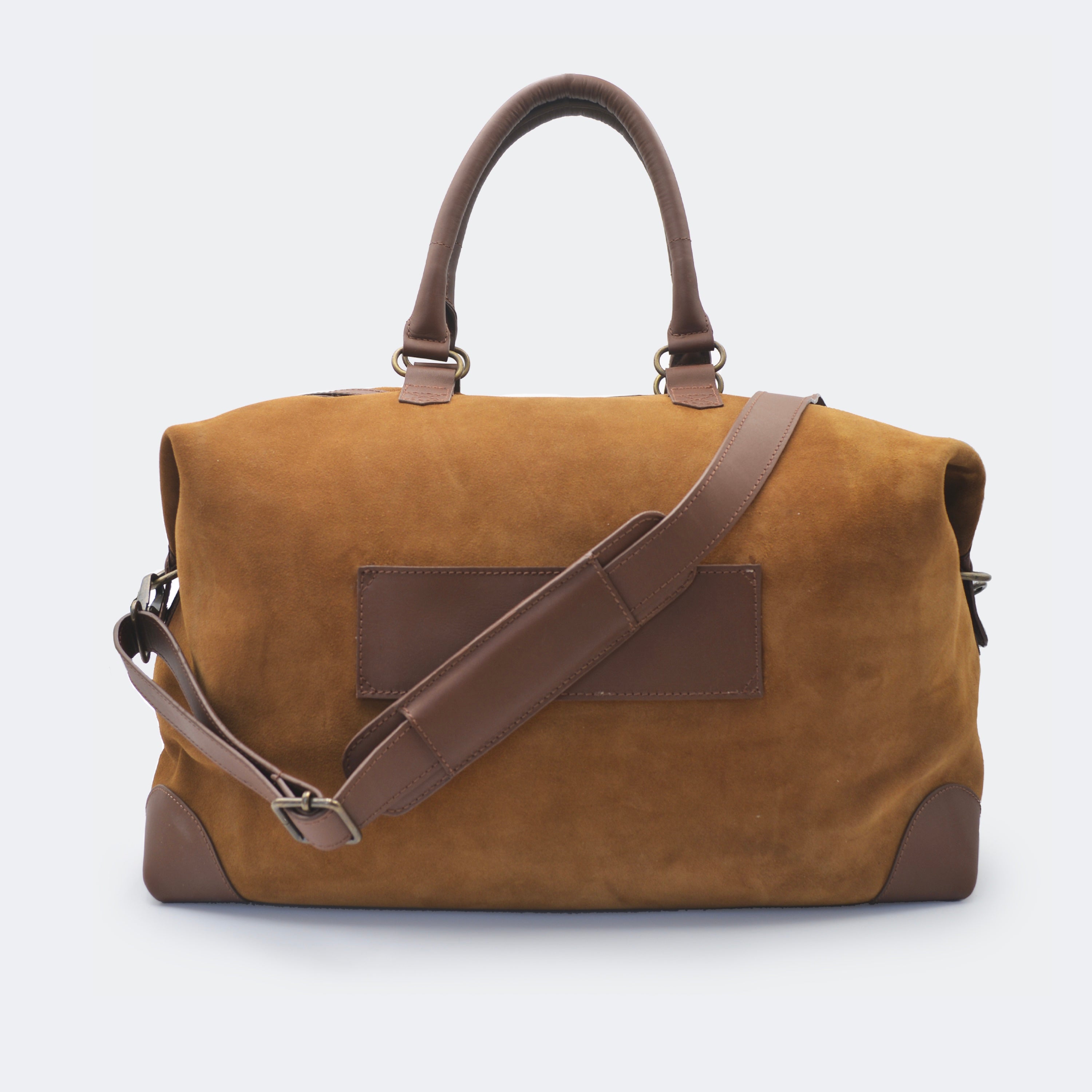 The Valise in brown leather shown from behind, highlighting the integrated luggage band designed to slide over a suitcase handle.