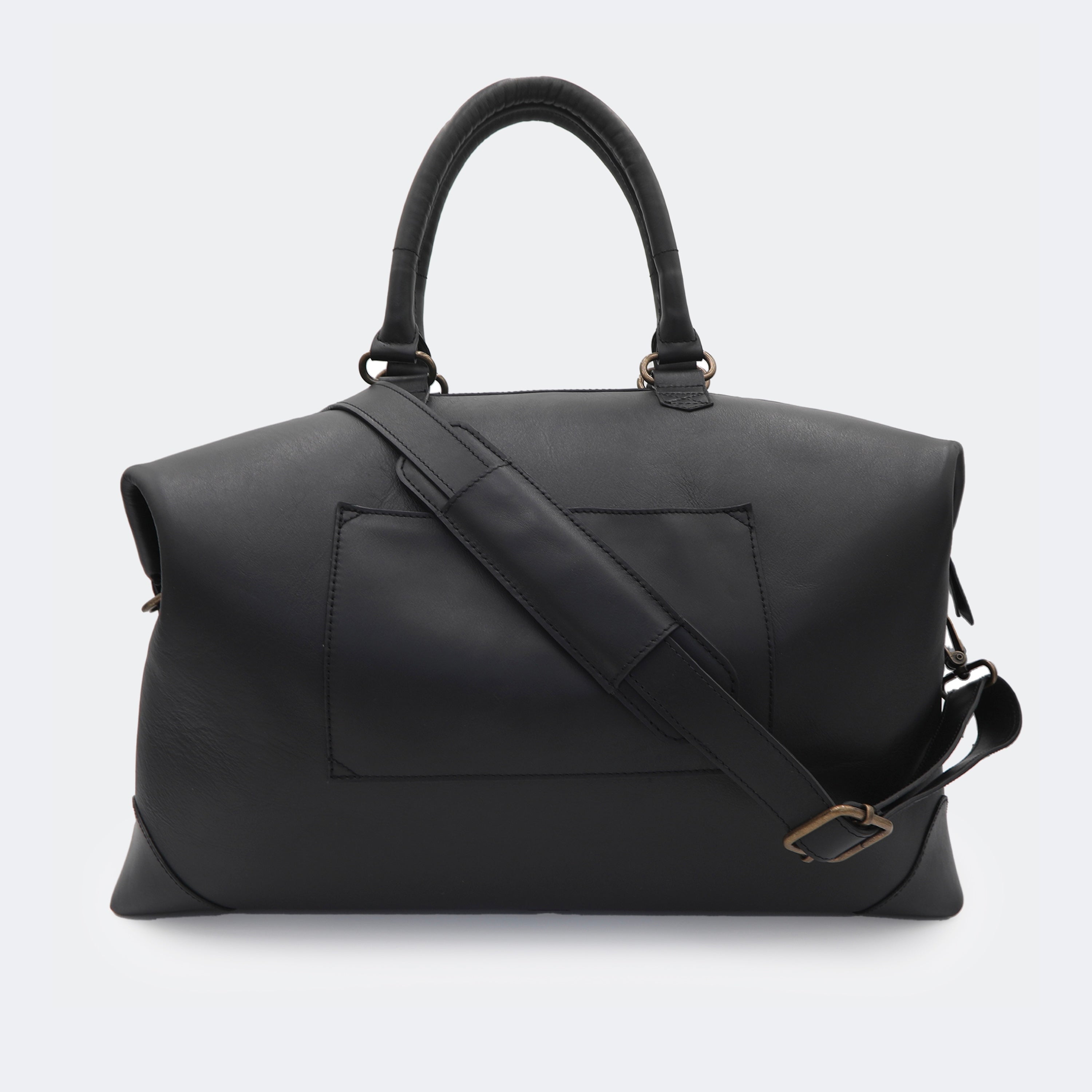 The Valise in black leather shown from behind, highlighting the integrated luggage band designed to slide over a suitcase handle.