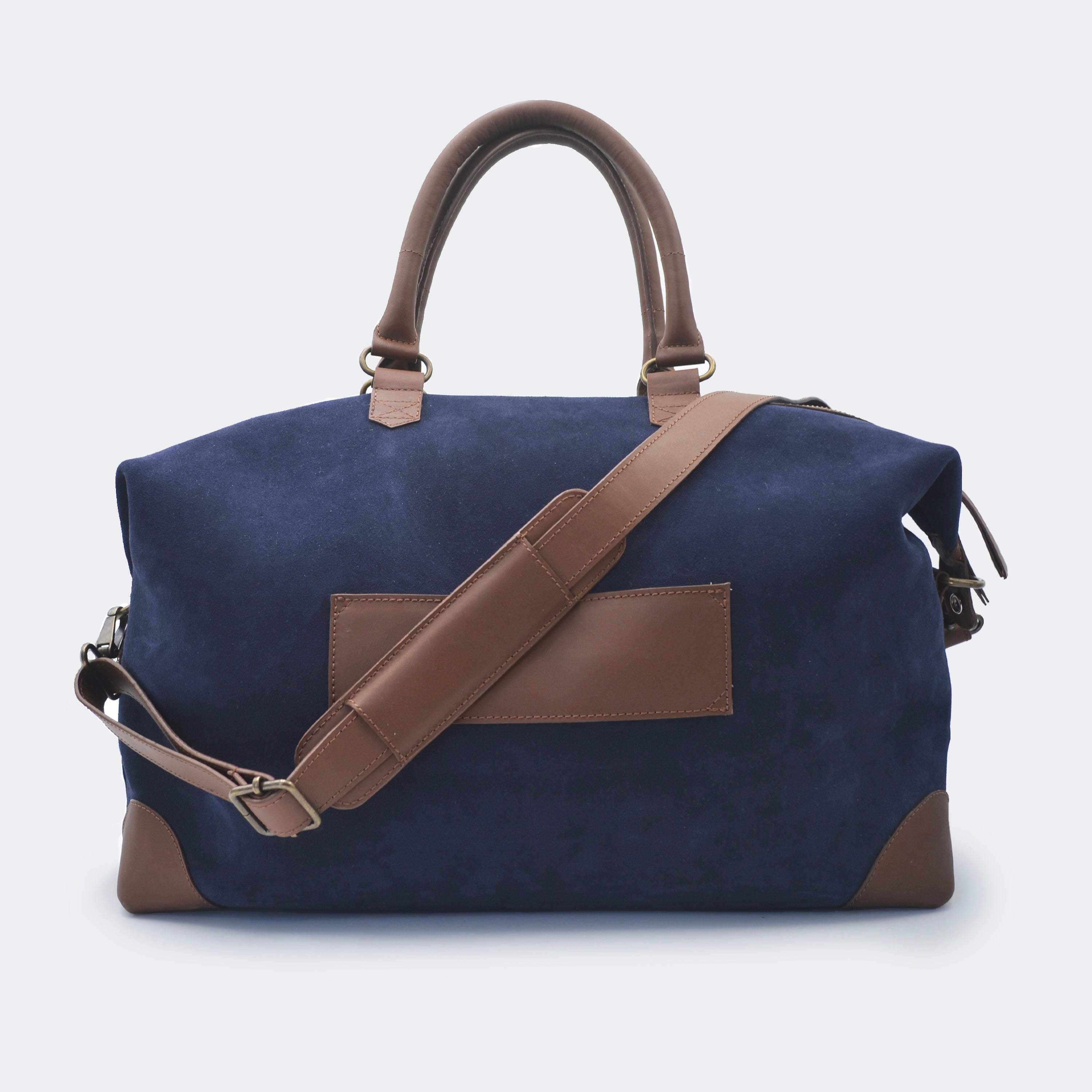 The Valise in navy blue leather shown from behind, highlighting the integrated luggage band designed to slide over a suitcase handle.