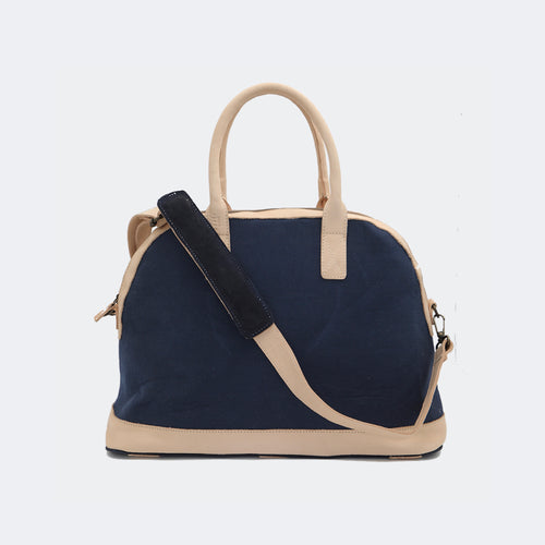 The Weekender in navy blue, shown with its removable leather shoulder strap attached — designed for comfortable, hands-free travel.