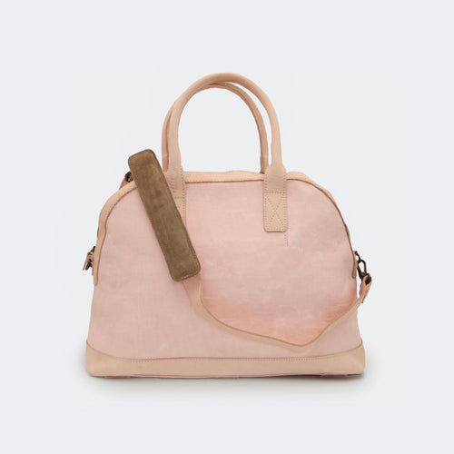 The Weekender in blush pink, shown with its removable leather shoulder strap attached — designed for comfortable, hands-free travel.
