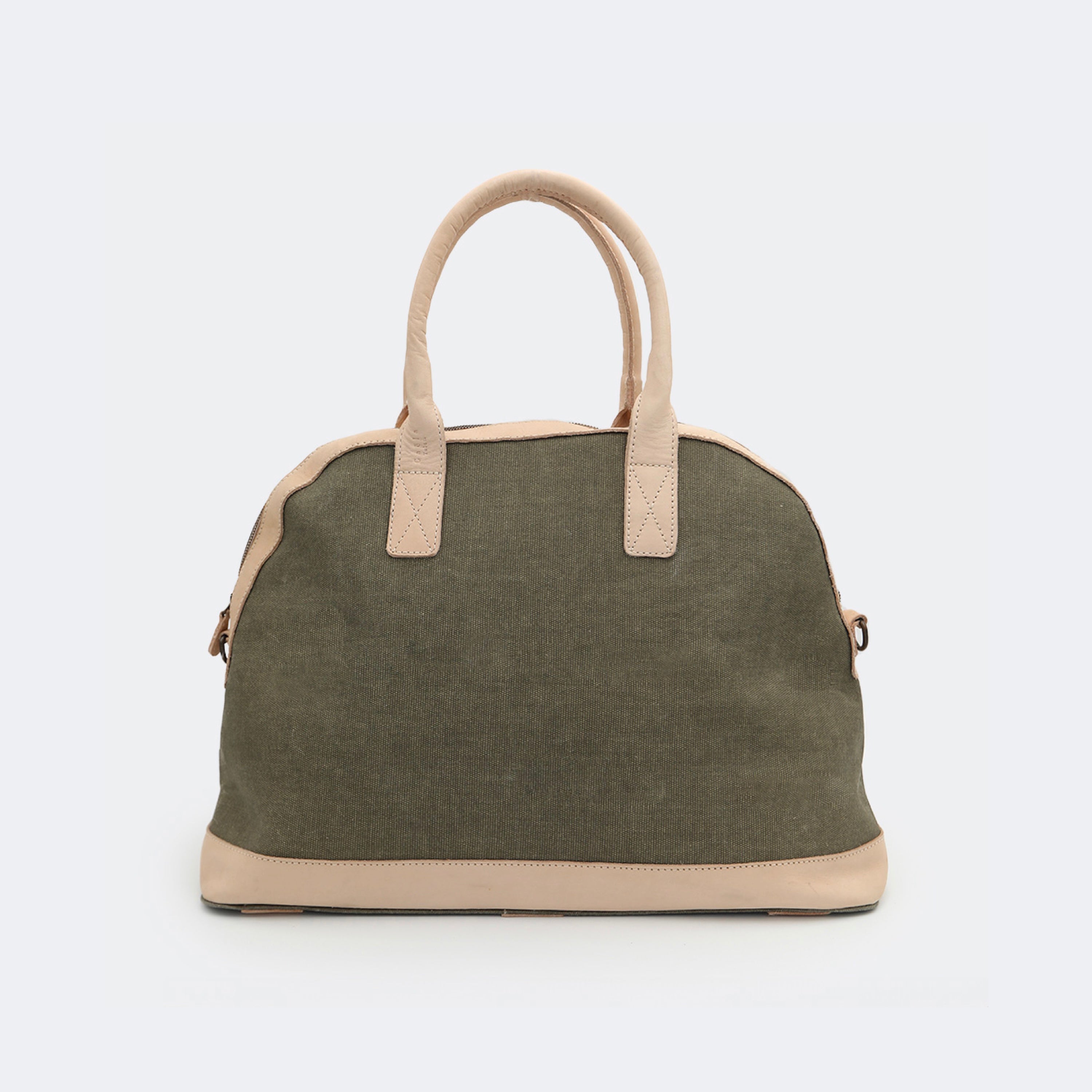 The Weekender in sage green, crafted from waxed cotton with full-grain leather accents — a spacious travel bag with a clean silhouette and curved handles.