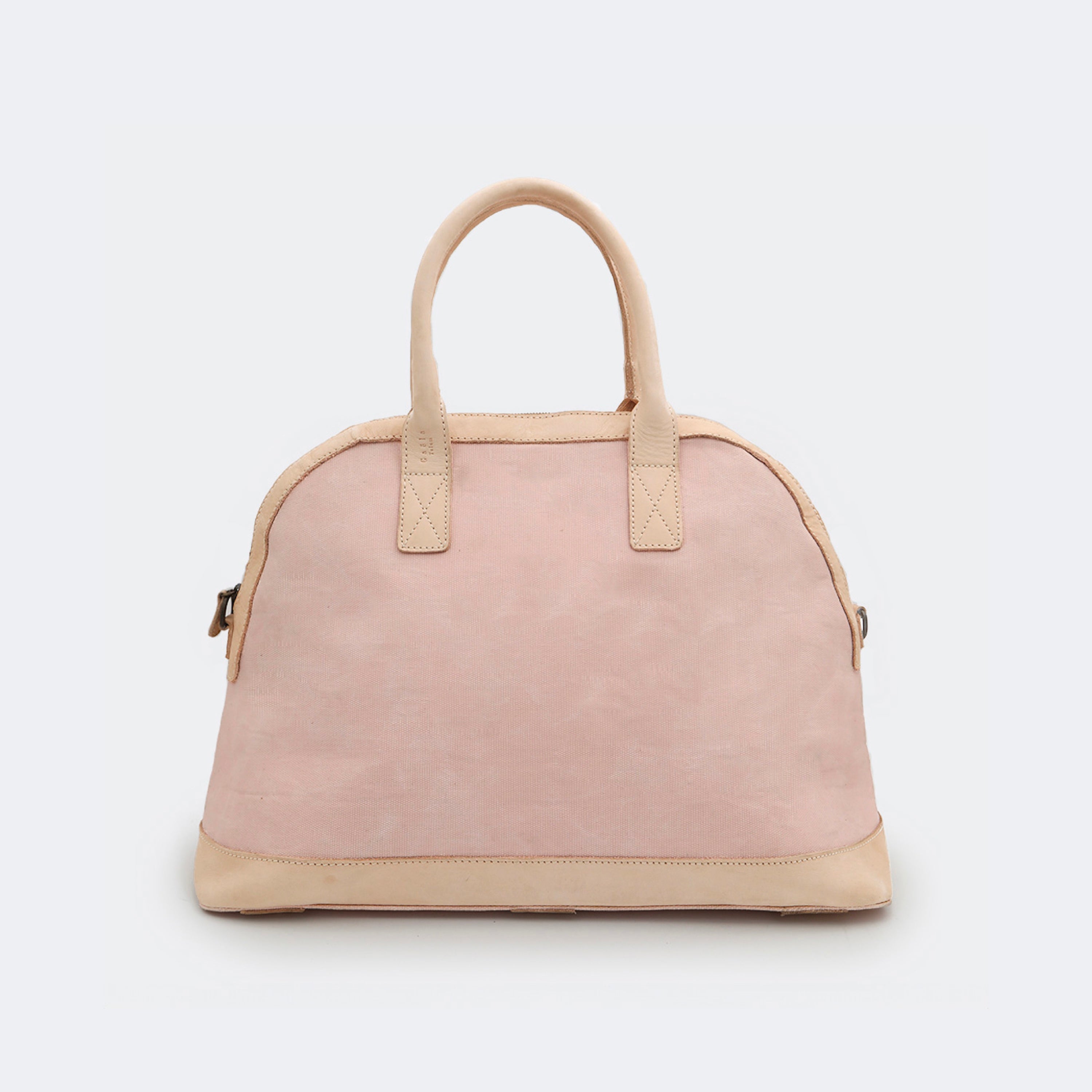 The Weekender in blush pink, crafted from waxed cotton with full-grain leather accents — a spacious travel bag with a clean silhouette and curved handles.