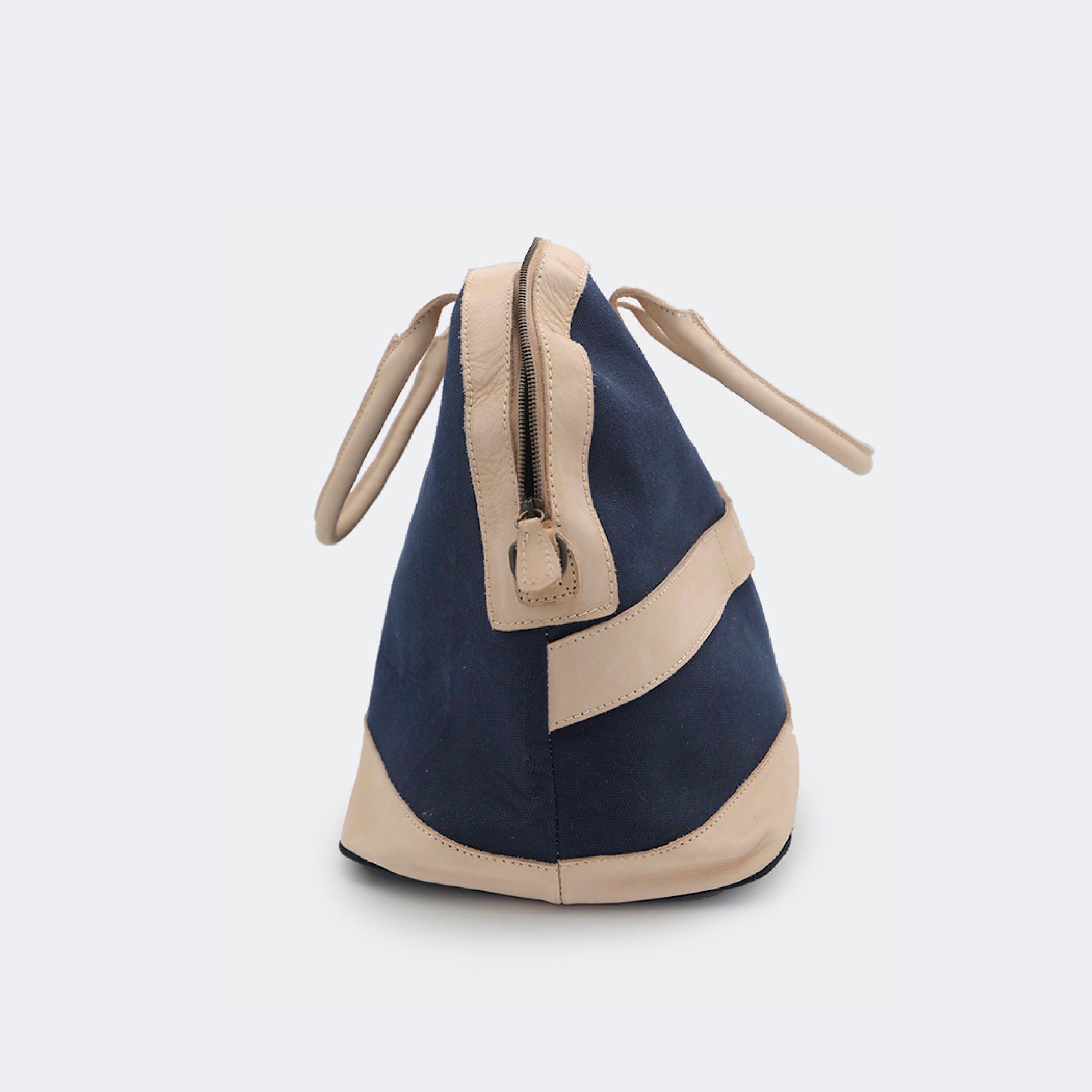 The Weekender in navy blue, crafted from cotton with full-grain leather accents — a spacious travel bag with a clean silhouette and curved handles.