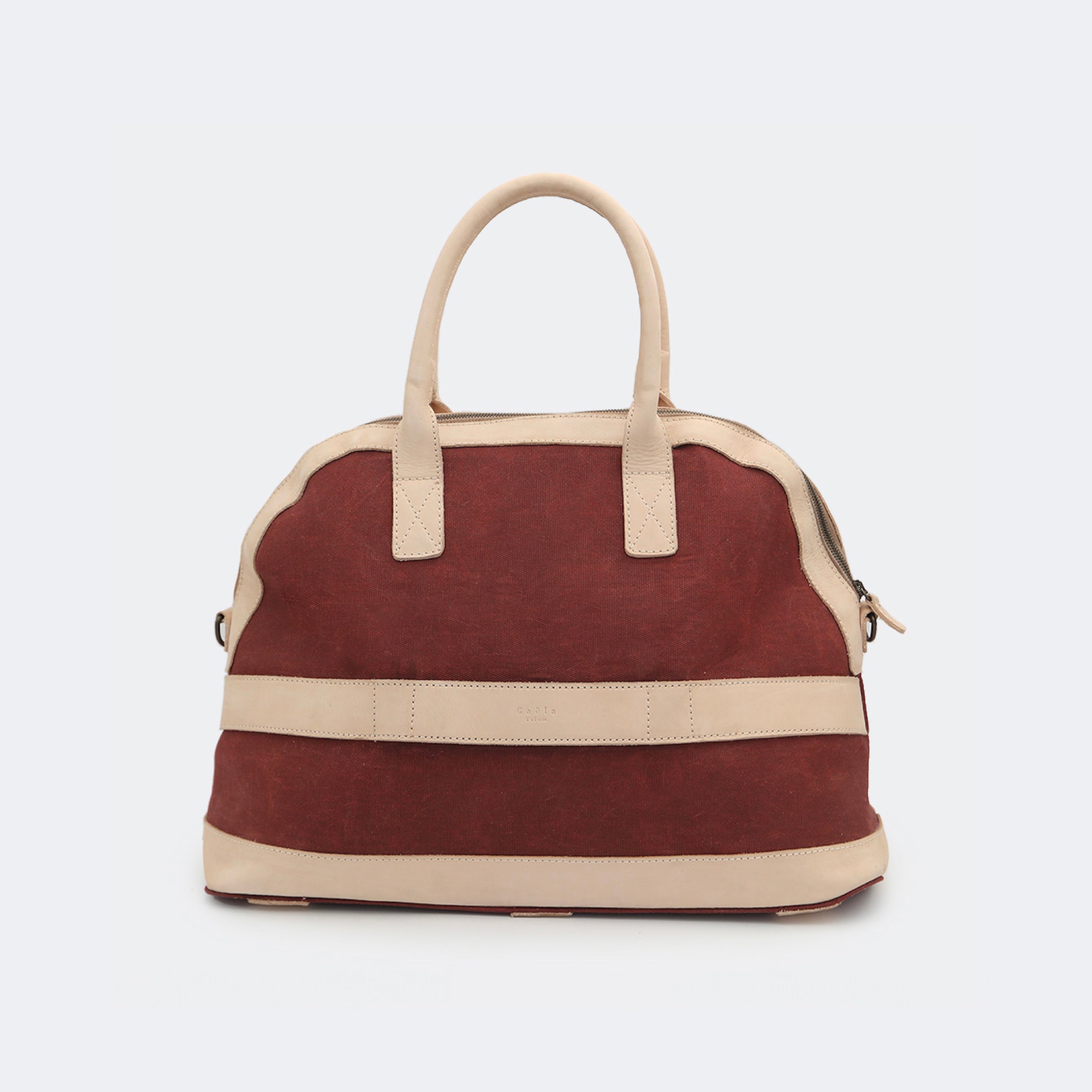 Back view of The Weekender in wine red, showing the built-in luggage band that slides over a suitcase handle for easy travel.