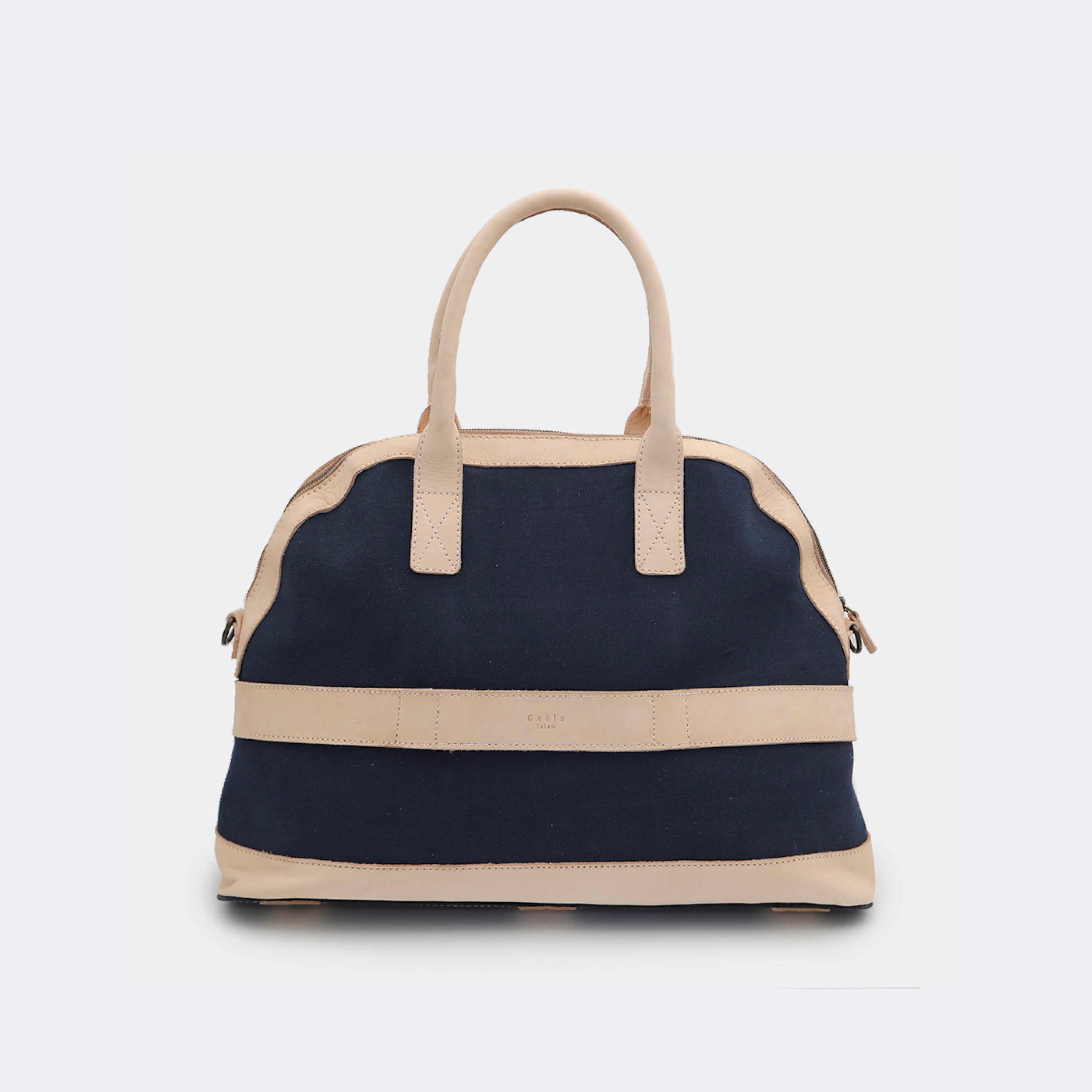 Back view of The Weekender in navy blue, showing the built-in luggage band that slides over a suitcase handle for easy travel.