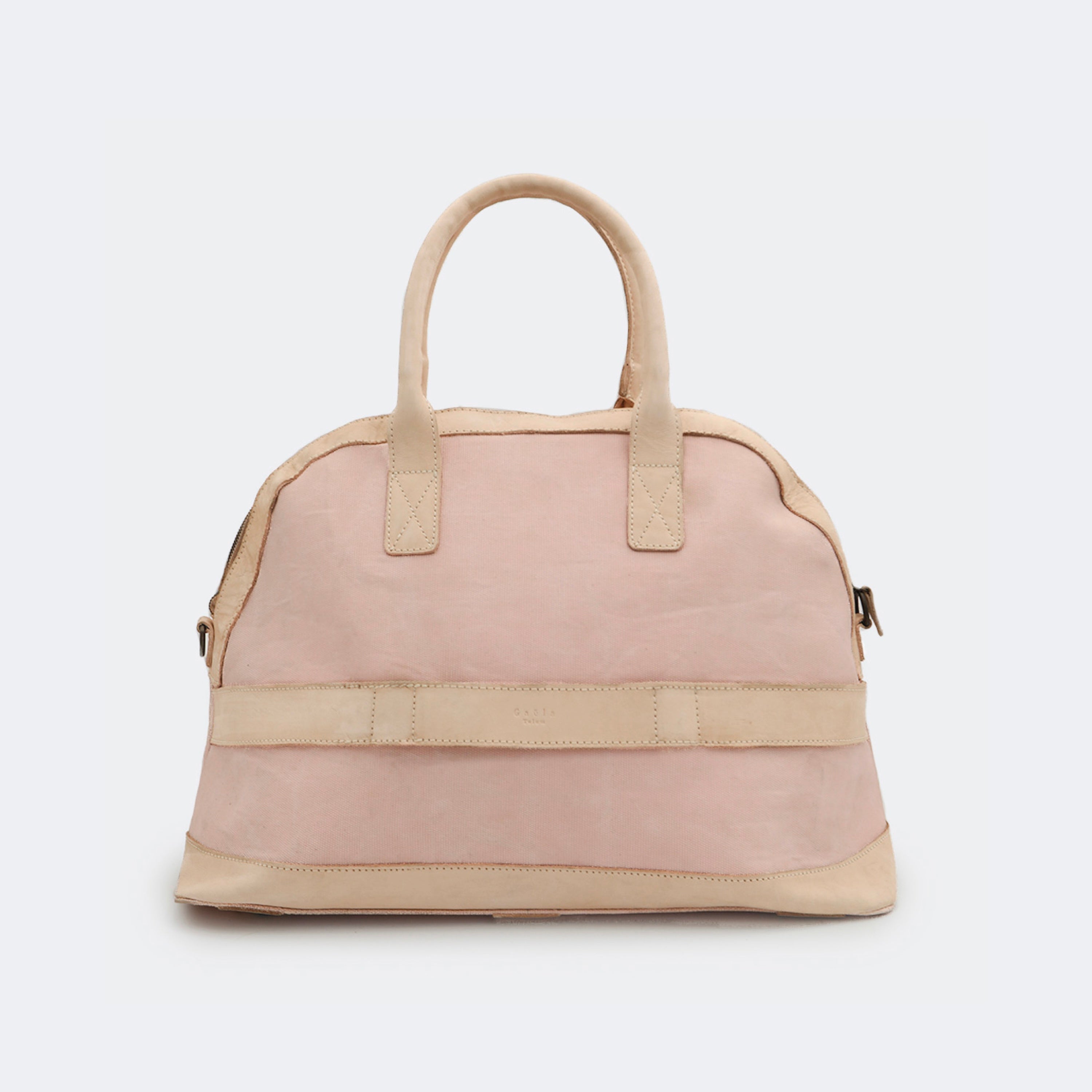 Back view of The Weekender in blush pink, showing the built-in luggage band that slides over a suitcase handle for easy travel.