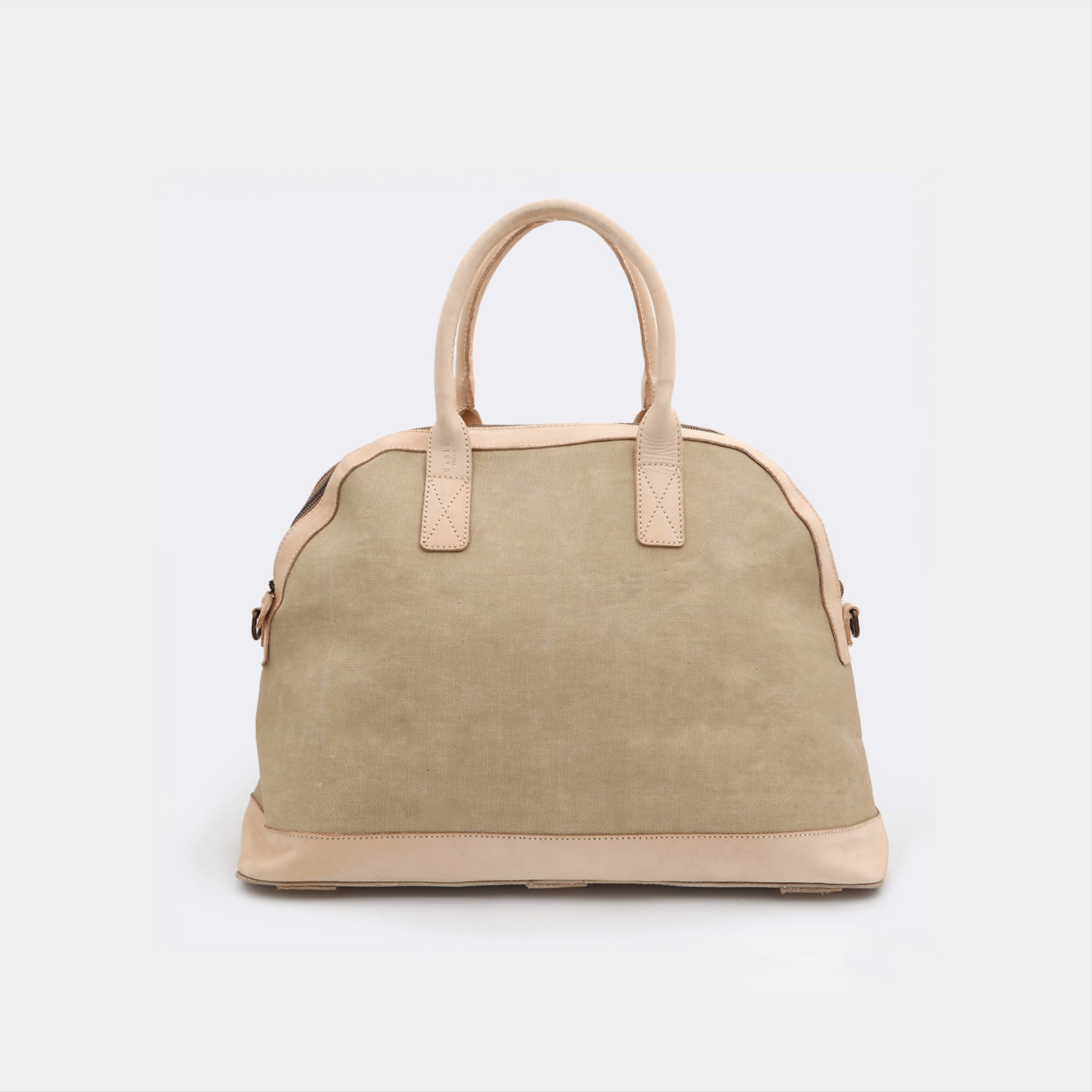The Weekender in tan, crafted from waxed cotton with full-grain leather accents — a spacious travel bag with a clean silhouette and curved handles.
